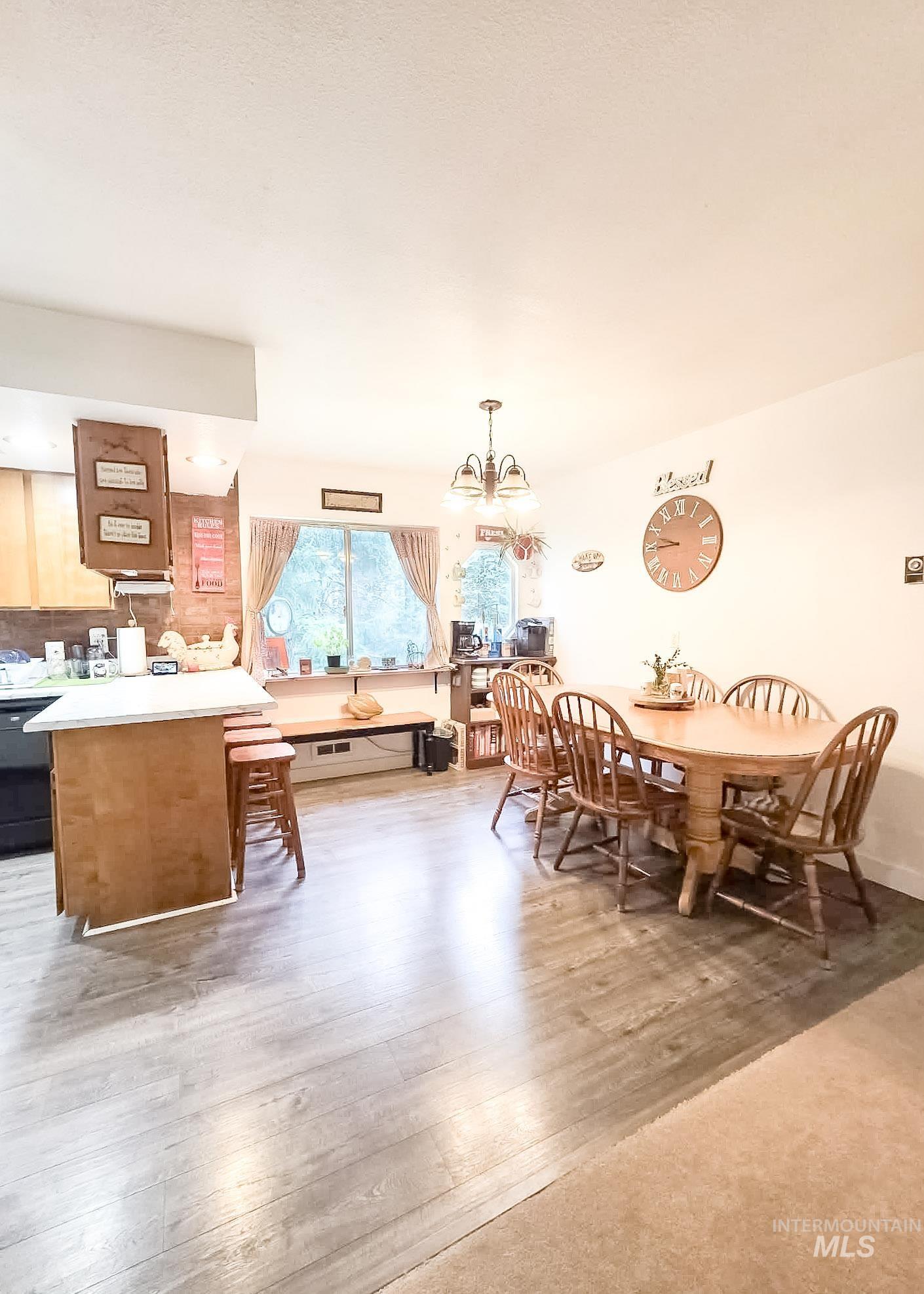 1650 Wells Bench Road Orofino, ID 83544 - Photo 8 of 44 Open-concept kitchen and dining area featuring wood-finish flooring, a kitchen island with white countertop, a window with natural light, and a ceiling-mounted light fixture