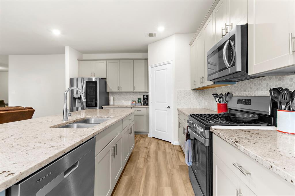 1211 Sweetleaf Street Melissa, TX 75454 - Photo 24 of 37 a kitchen with stainless steel appliances granite countertop a sink stove and refrigerator