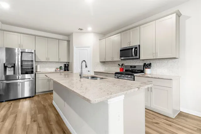 a kitchen with stainless steel appliances granite countertop a sink refrigerator and microwave