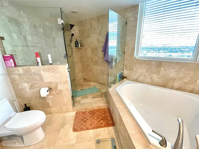 a bath tub sitting next to a white toilet and a shower