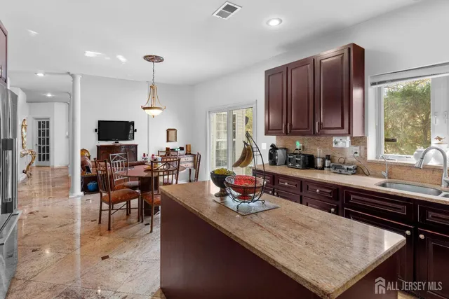 a kitchen with stainless steel appliances granite countertop a stove top oven a sink dishwasher a dining table and chairs with wooden floor