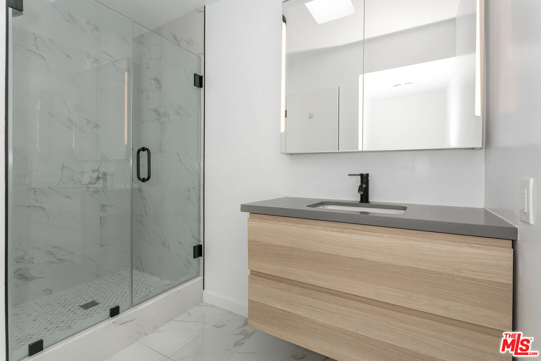 560 North Kings Road, Unit 2 West Hollywood, CA 90048 - Photo 7 of 12 a bathroom with a granite countertop sink a mirror and shower