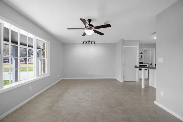 a view of an empty room and chandelier fan