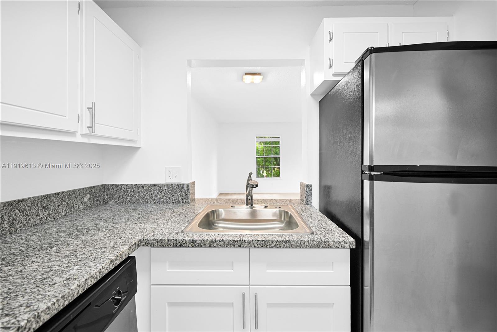 7550 Stirling Road, Unit A107 Davie, FL 33024 - Photo 26 of 27 a kitchen with granite countertop a sink and a refrigerator