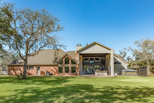 a view of a big house with a big yard and large trees