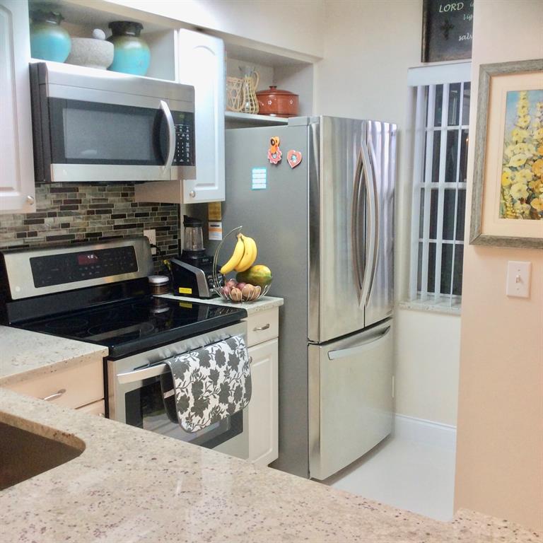 Undisclosed Address Pompano Beach, FL 33069 - Photo 8 of 23 a kitchen with stainless steel appliances a stove a refrigerator and a microwave