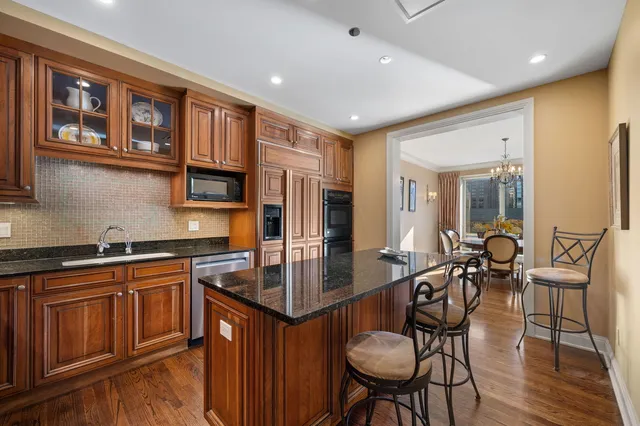 a kitchen with stainless steel appliances granite countertop a stove a sink dishwasher a dining table and chairs with wooden floor