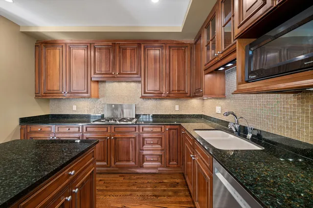 a kitchen with granite countertop stainless steel appliances sink stove and cabinets
