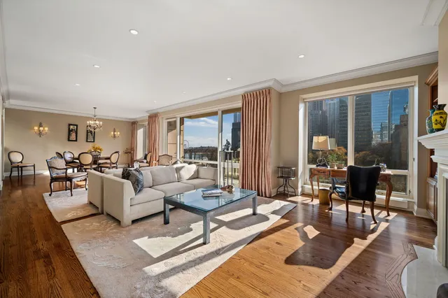 a living room with furniture large windows and wooden floor