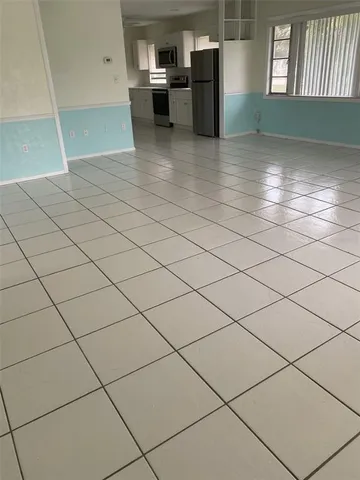 a kitchen with granite countertop a refrigerator and white cabinets