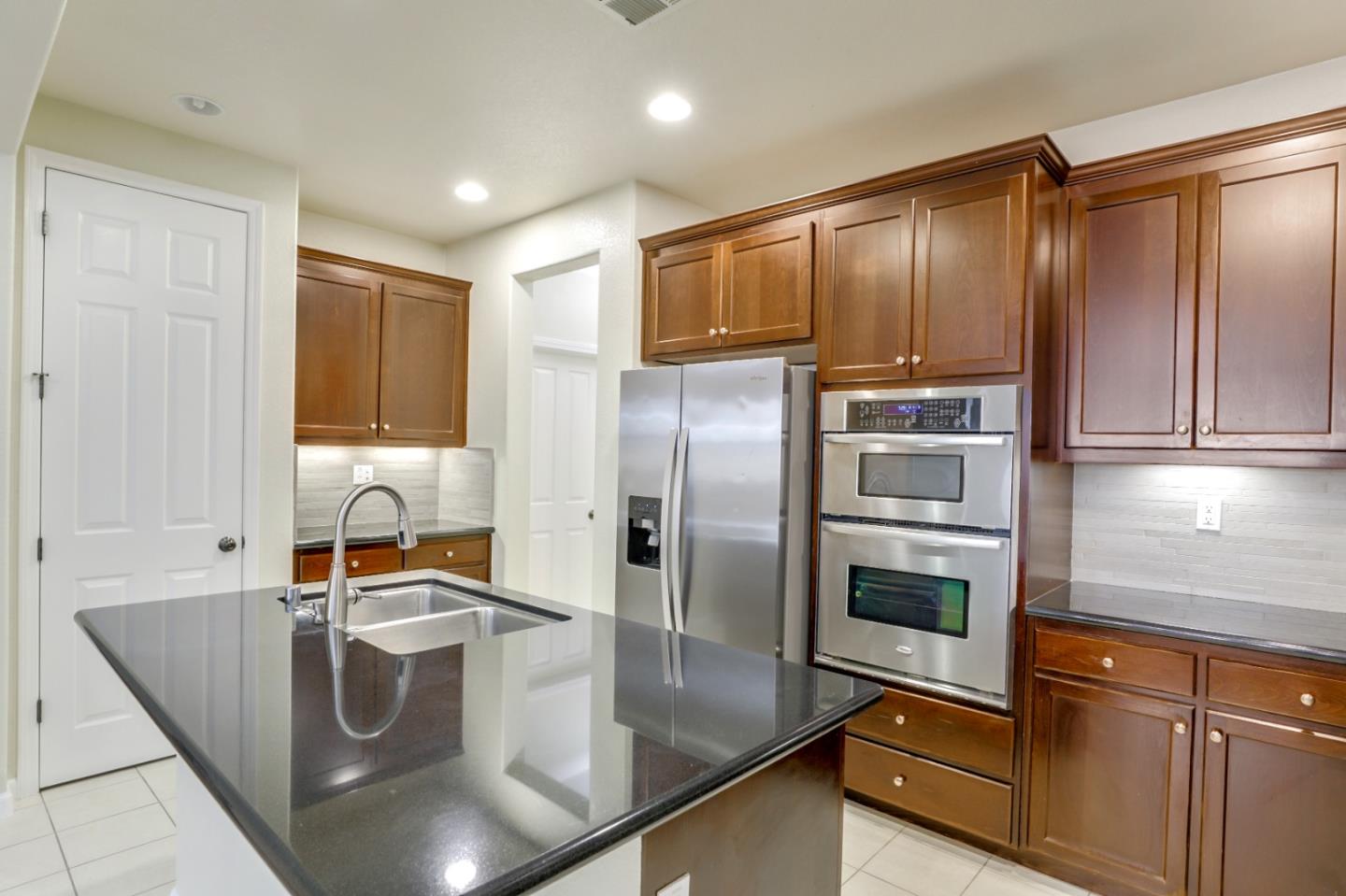 5090 Fioli Loop San Ramon, CA 94582 - Photo 4 of 36 a kitchen with kitchen island granite countertop a sink refrigerator and microwave