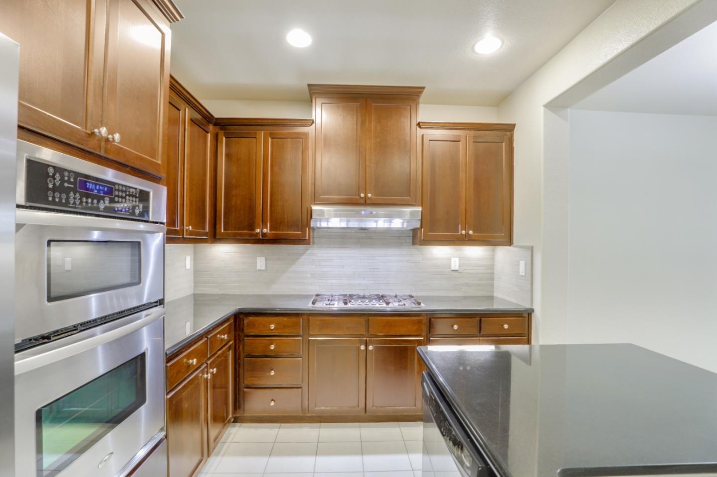 5090 Fioli Loop San Ramon, CA 94582 - Photo 6 of 36 a kitchen with granite countertop a stove and a microwave
