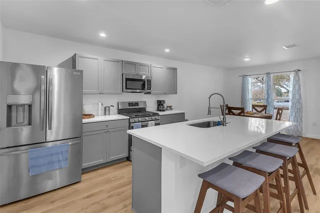 a kitchen with stainless steel appliances a table chairs refrigerator and microwave