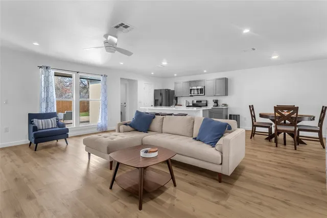 a living room with furniture and a dining table with wooden floor