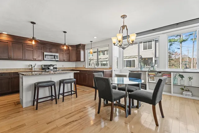 a dining room with stainless steel appliances kitchen island granite countertop a table chairs and a chandelier