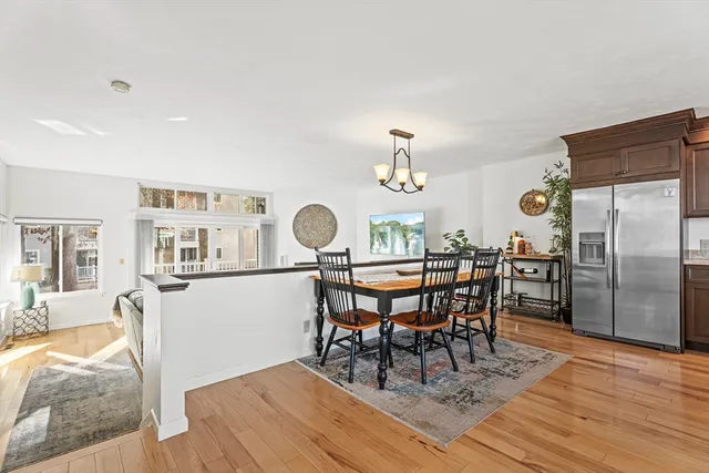 a dining room with wooden floor a chandelier a wooden table and chairs