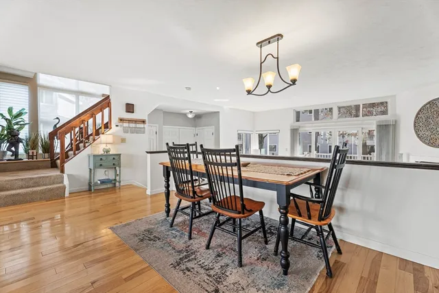 a dining room with wooden floor a chandelier a wooden table and chairs