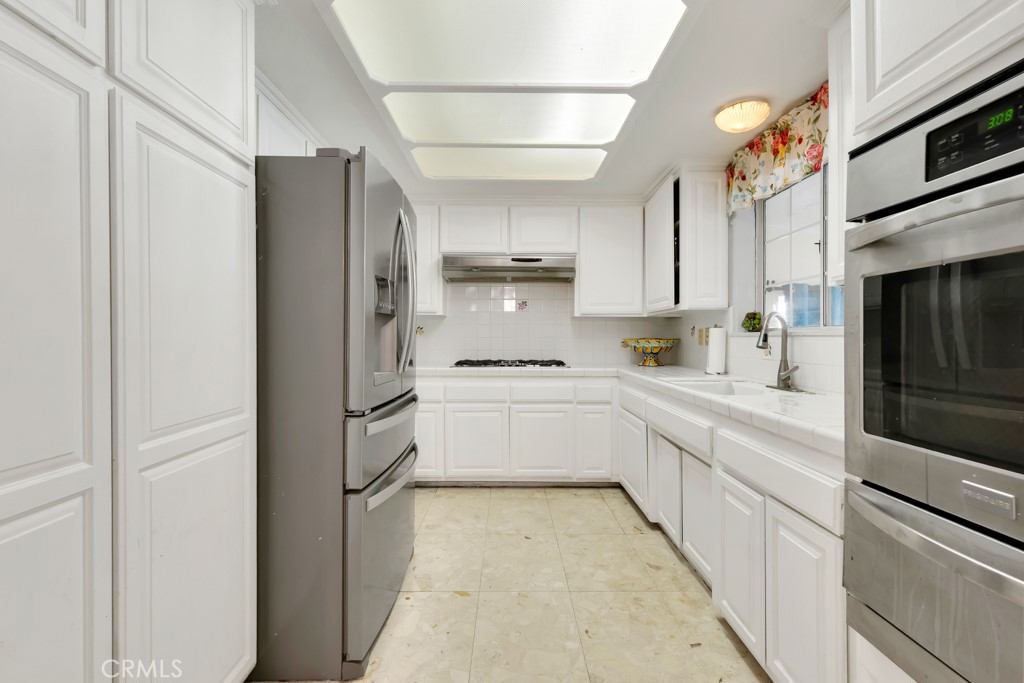14024 Tyler Street Sylmar, CA 91342 - Photo 15 of 50 a kitchen with white cabinets and refrigerator
