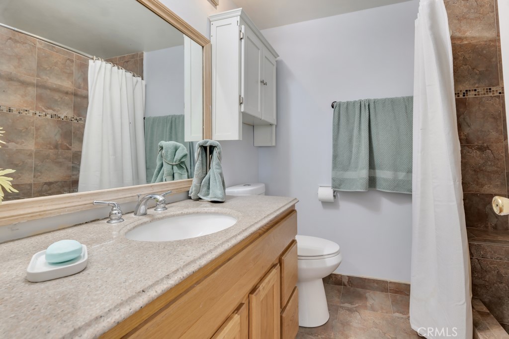 14024 Tyler Street Sylmar, CA 91342 - Photo 32 of 50 a bathroom with a granite countertop sink a toilet and a mirror