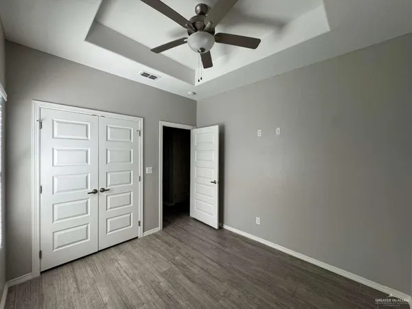 an empty room with wooden floor ceiling fan and windows
