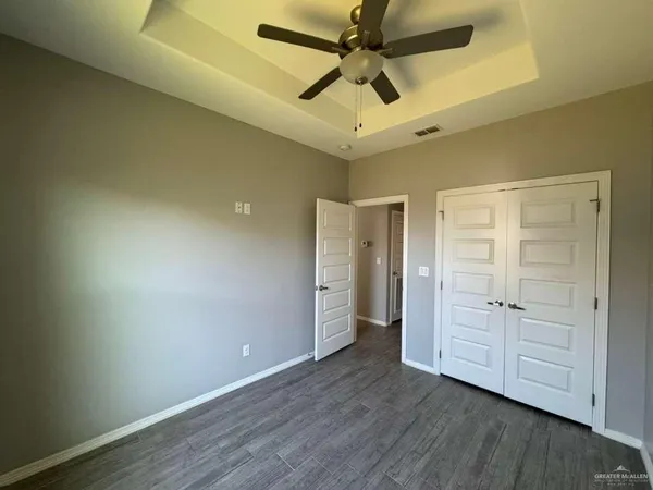 an empty room with closet and a ceiling fan