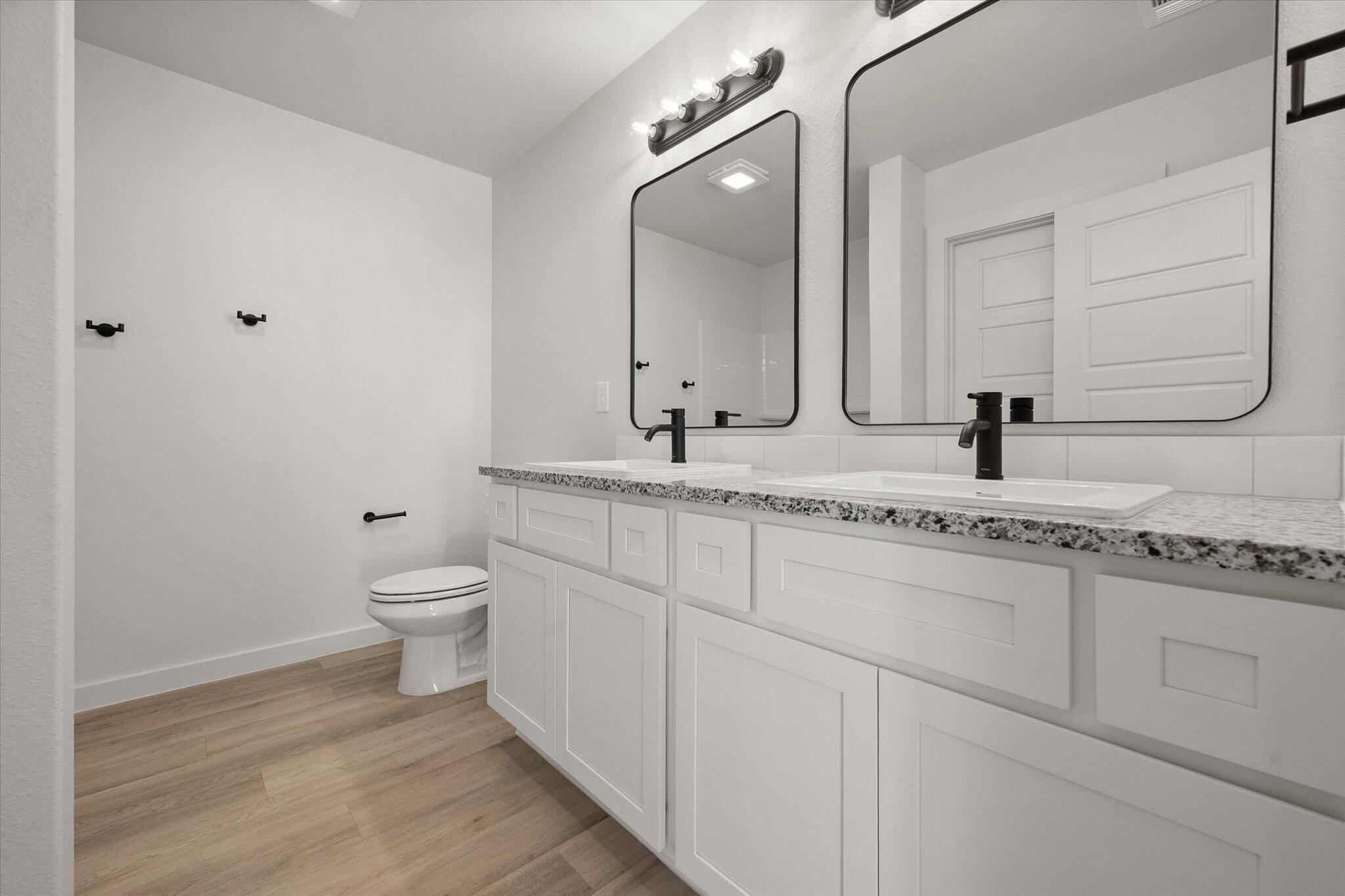 3113 140th Street Lubbock, TX 79423 - Photo 14 of 22 a bathroom with a granite countertop sink a toilet and a mirror