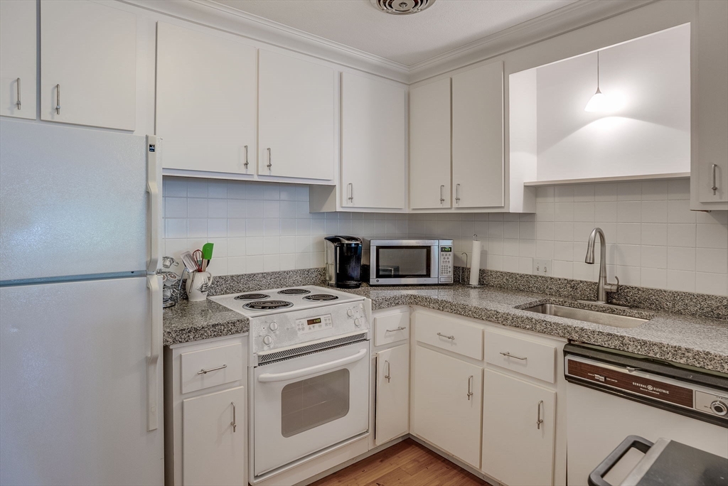 36 Whitman Road, Unit 24 Waltham, MA 02453 - Photo 6 of 14 a kitchen with granite countertop white cabinets and white appliances