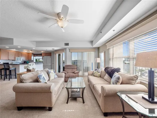a living room with furniture ceiling fan and a large window