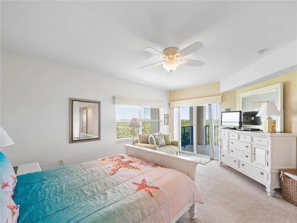 a bedroom with a large bed and a chandelier fan