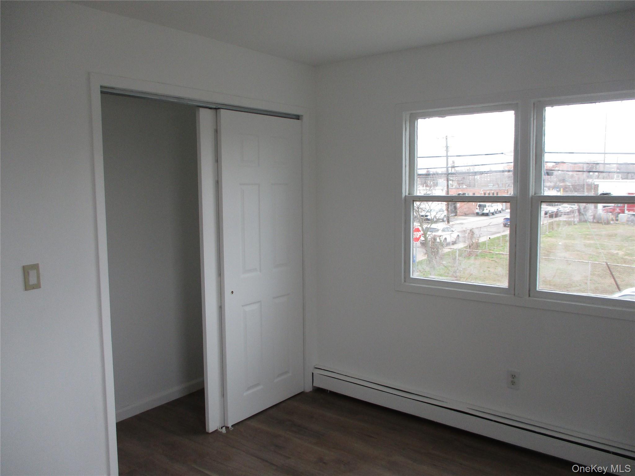 94 Roger Avenue Inwood, NY 11096 - Photo 7 of 19 an empty room with wooden floor and windows