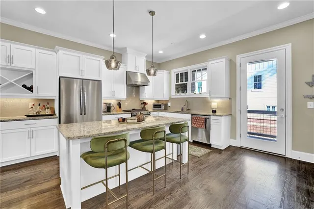 a kitchen with a refrigerator a stove and white cabinets with wooden floor