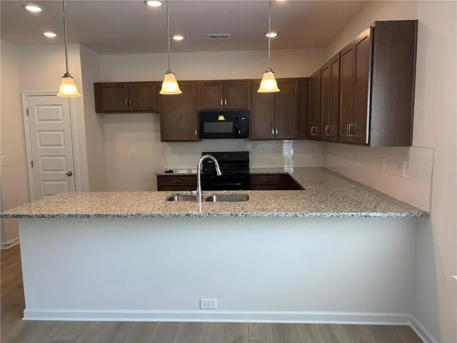 a large kitchen with stainless steel appliances a large counter top a stove a refrigerator and a sink