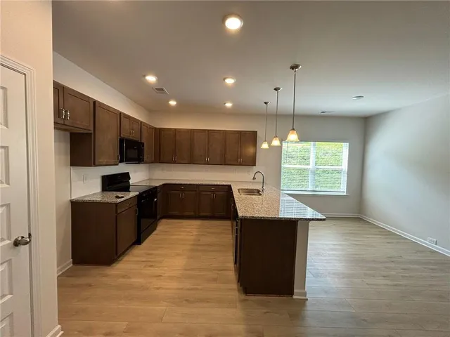 a view of an empty room and a kitchen