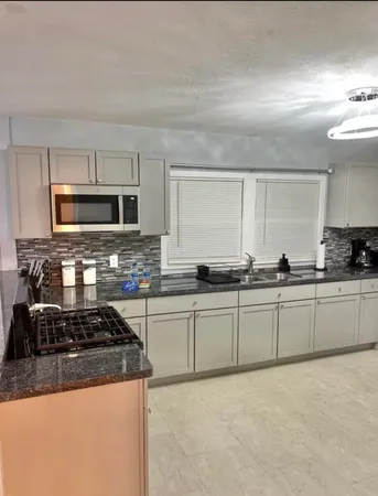 a large kitchen with granite countertop a stove top oven a sink a counter space and cabinets