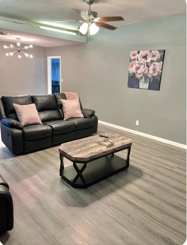 a living room with couches and a dining table with wooden floor