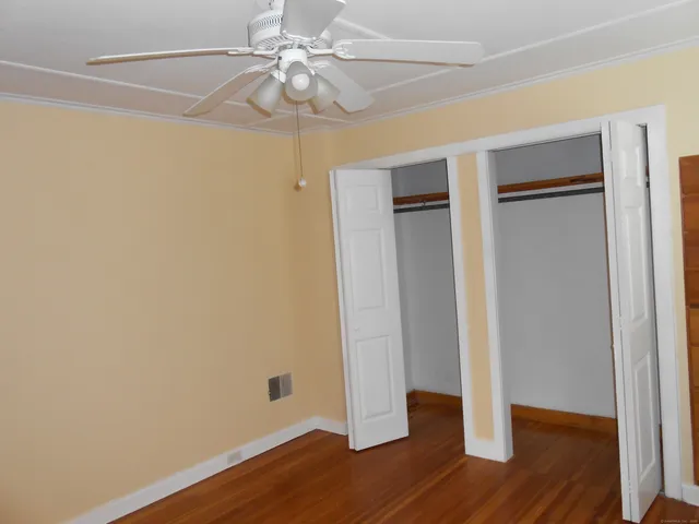 an empty room with wooden floor and ceiling fan