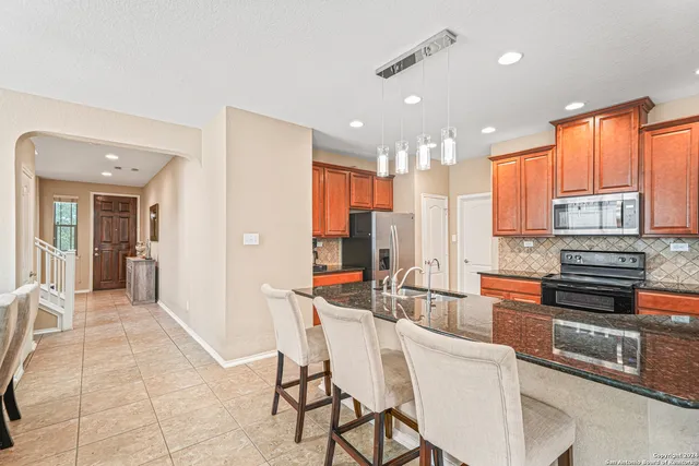 a kitchen with stainless steel appliances granite countertop a sink refrigerator and cabinets