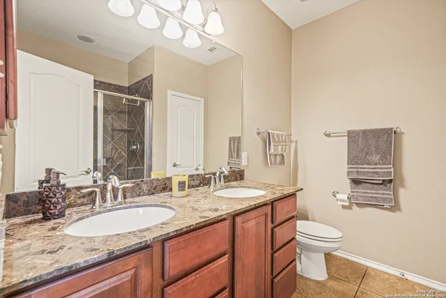a en suite bathroom with a granite countertop sink a mirror and shower