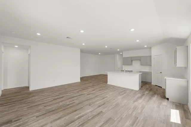 a view of kitchen with kitchen island wooden floors appliances and cabinets