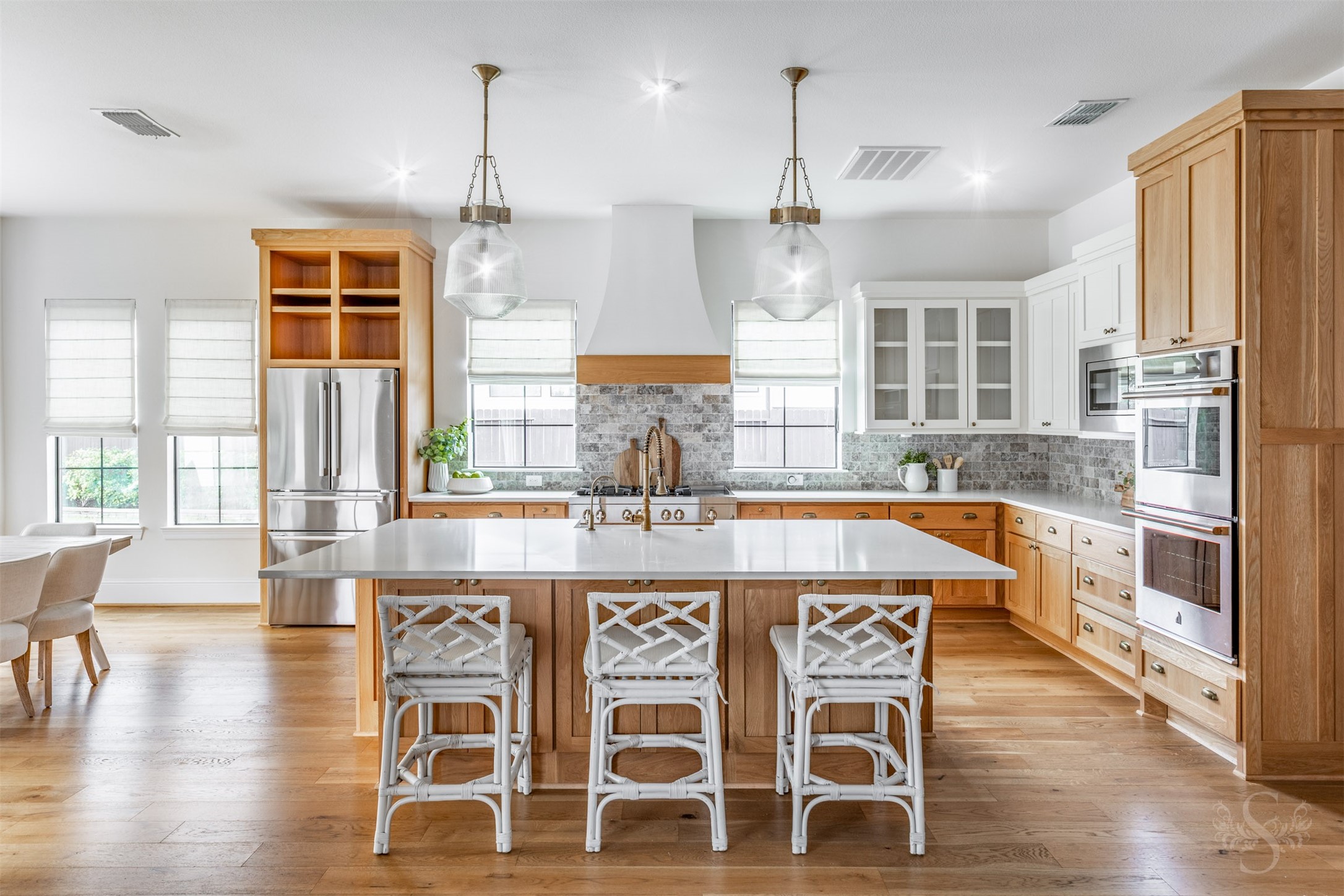 27919 Indigo Ridge Drive Fulshear, TX 77441 - Photo 5 of 50 This stunning chef-inspired kitchen showcases a huge Quartz island with seating, custom pendant lighting, and a gorgeous blend of warm wood cabinetry and crisp white glass-front uppers. High-end stainless steel appliances, double ovens, designer backsplash, and abundant natural light create a space that’s as functional as it is beautiful.