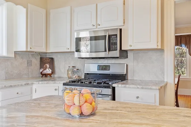 a kitchen with stainless steel appliances granite countertop a stove a sink and a white cabinets