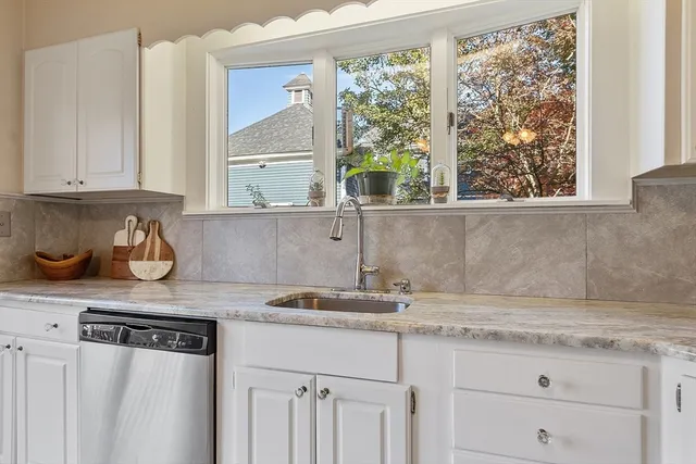 a kitchen with granite countertop a window a sink and white cabinets