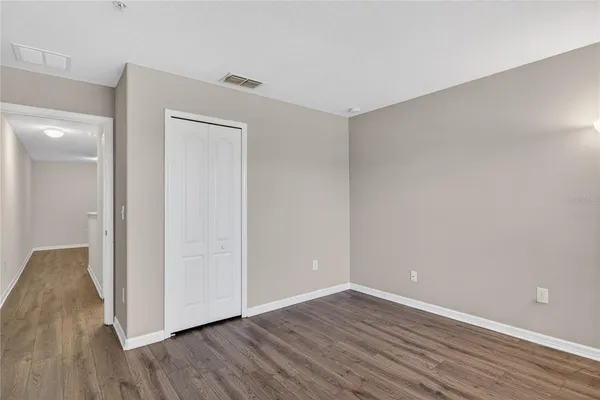 a view of an empty room with wooden floor and closet