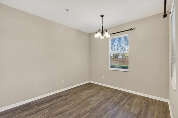 a view of an empty room with window and wooden floor