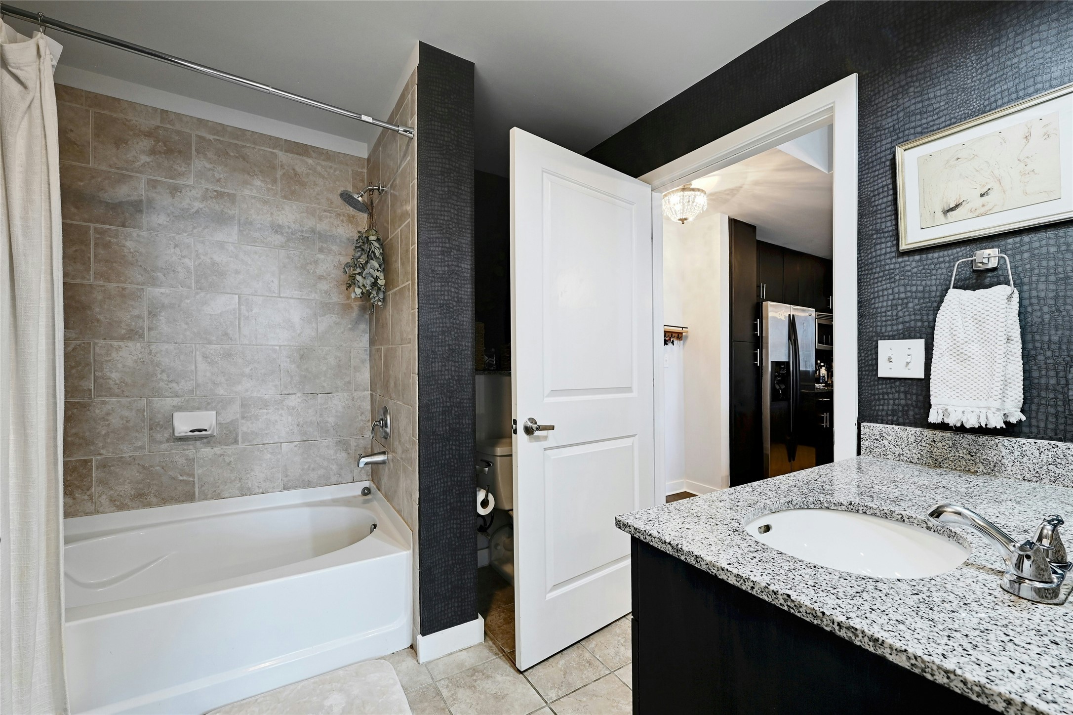 360 Nueces Street, Unit 1809 Austin, TX 78701 - Photo 20 of 25 Bathroom featuring a built-in bathtub with tiled surround, a vanity with a granite countertop, and an undermount sink