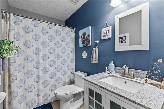 a bathroom with a granite countertop sink a toilet and a mirror