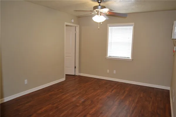 an empty room with wooden floor chandelier fan and windows