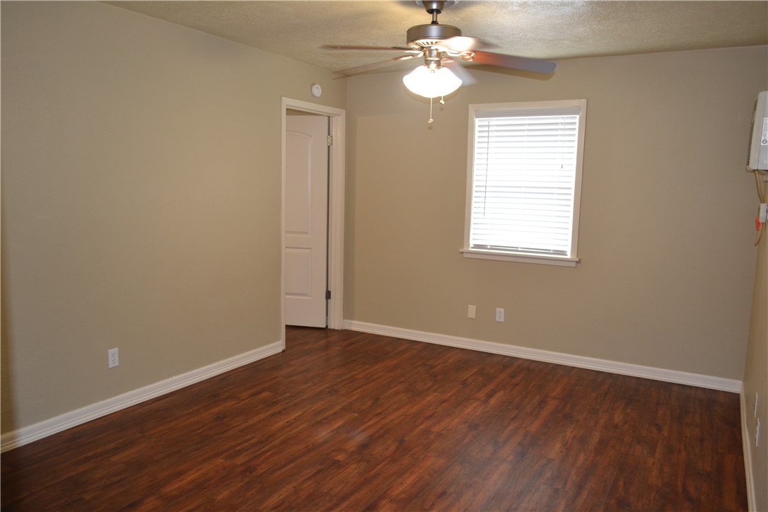 4212 Old College Road, Unit 7 Bryan, TX 77801 - Photo 6 of 19 an empty room with wooden floor chandelier fan and windows