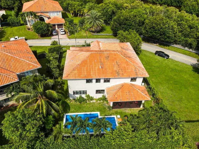 an aerial view of a house with swimming pool and large trees