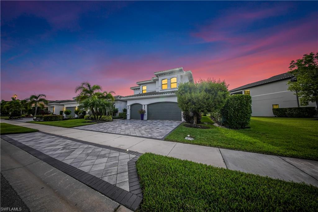 Mediterranean / spanish home featuring a yard, an attached garage, decorative driveway, stucco siding, and a tiled roof
